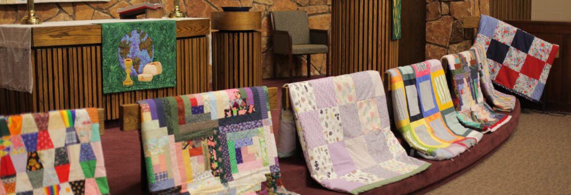 Quilts made by women of Lord of Love are displayed near the altar in preparation for a blessing before they are donated to Lutheran World Relief